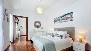 Un dormitorio con cama, mesita de noche y un cuadro en la pared.