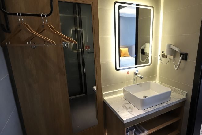 Un baño moderno con cabina de ducha de vidrio, un lavabo blanco y un espejo con iluminación integrada.