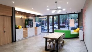 A modern interior with a reception desk, a dining area, and large windows offering a view of the street. - Shell Hotel (Chengyang Agricultural University Subway Station) (Qingdao)