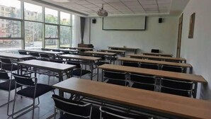 A classroom with rows of desks and chairs, large windows, a projector screen, and a whiteboard. - Shell Hotel (Chengyang Agricultural University Subway Station) (Qingdao)