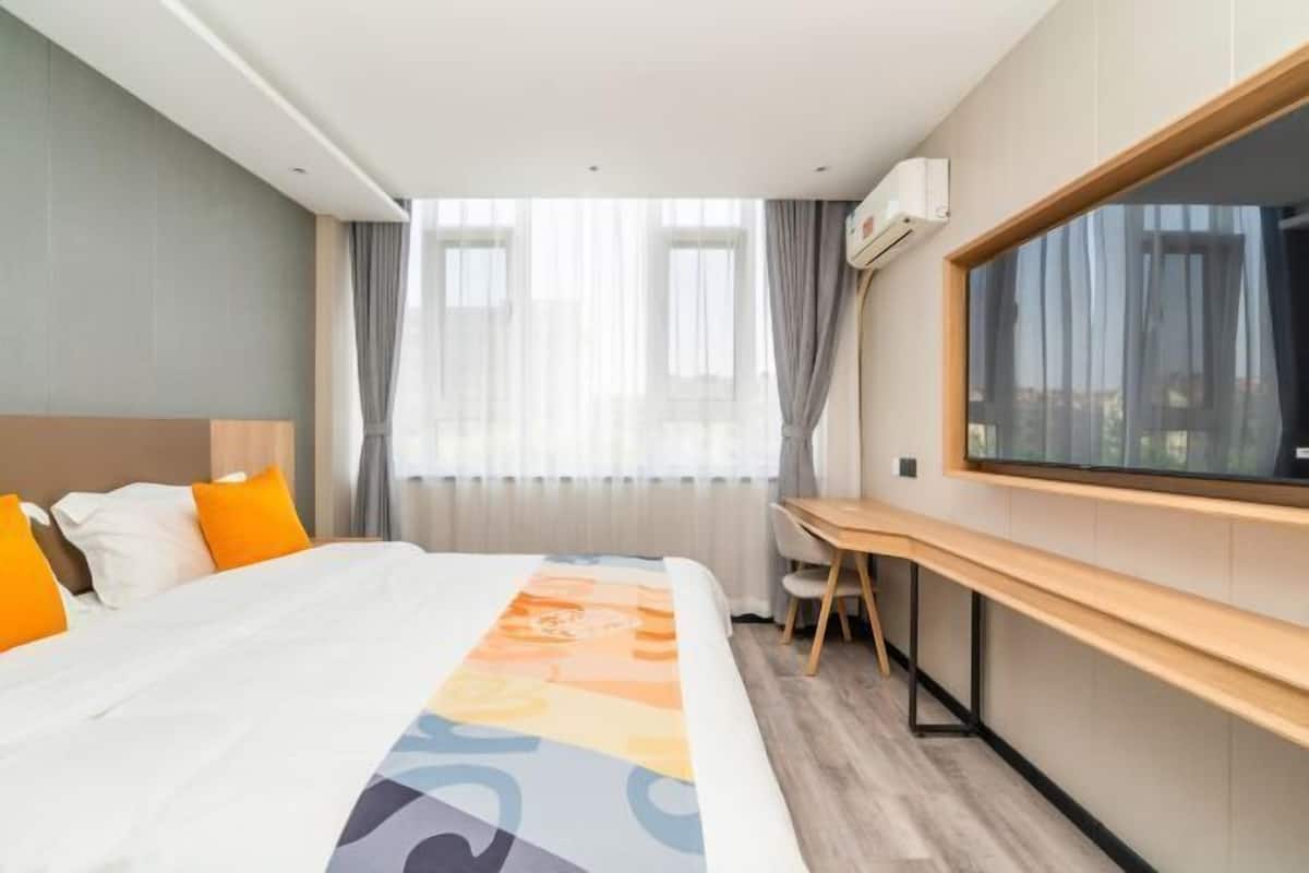 Une chambre d’hôtel avec un lit, un bureau et une grande fenêtre.