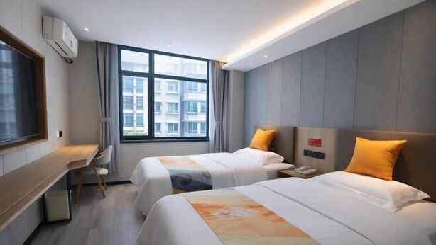 A hotel room with two beds, a desk, and a window with a view of buildings. - Shell Hotel (Chengyang Agricultural University Subway Station) (Qingdao)