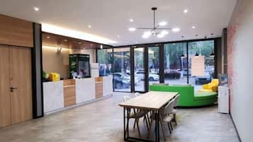 Un intérieur moderne comprenant un comptoir d’accueil, un espace détente et de grandes fenêtres offrant une vue sur l’extérieur.