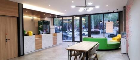 A modern interior with a reception desk, seating area, and large windows offering a view of the outdoors.