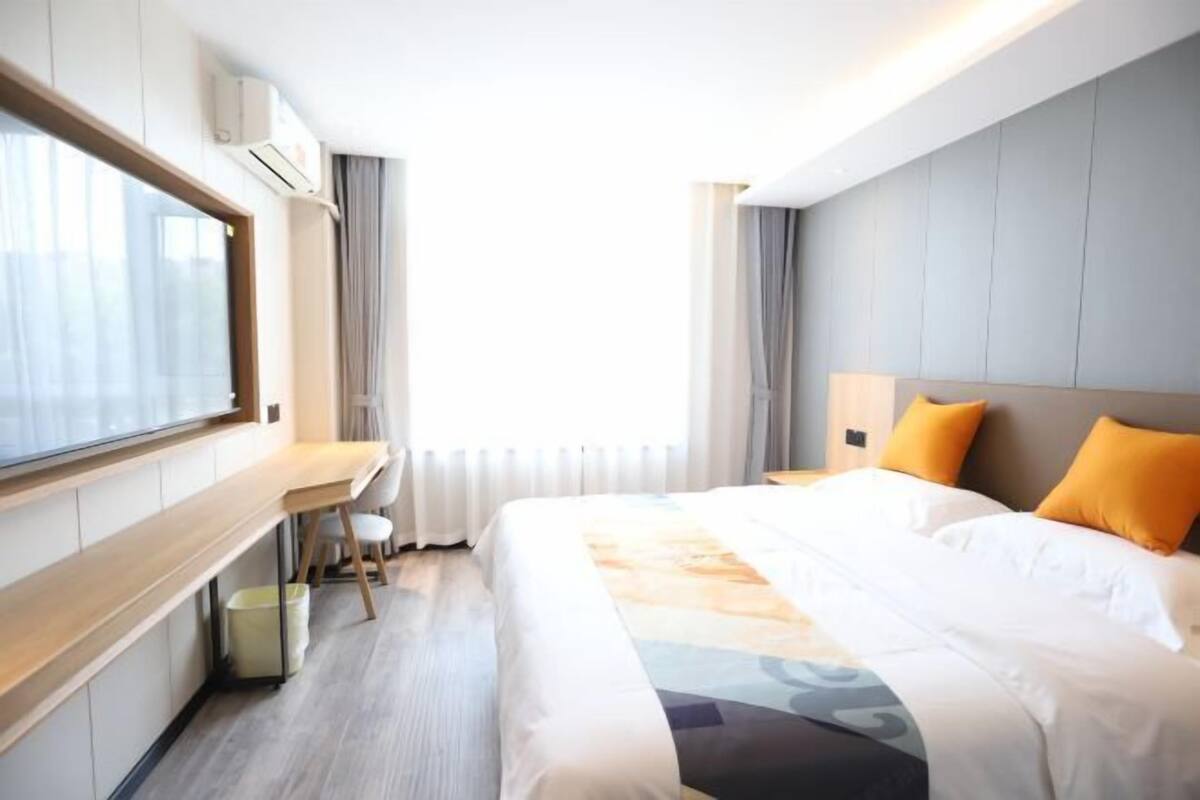 Une chambre d’hôtel moderne avec un grand lit, un bureau et une fenêtre.