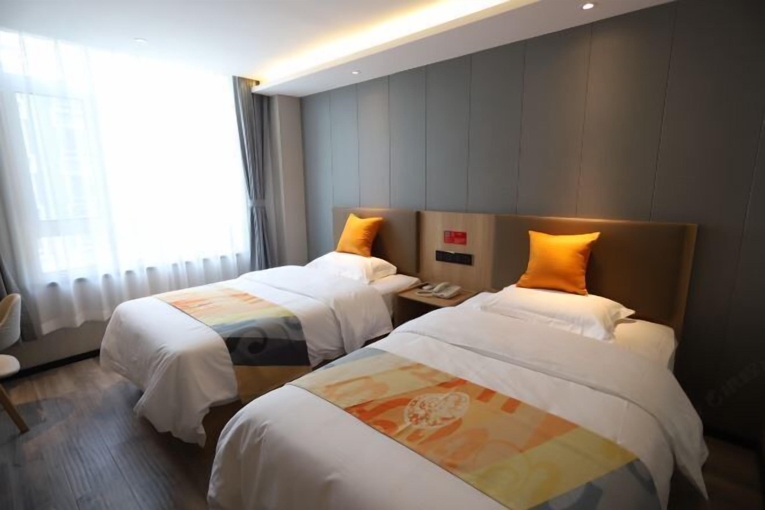 A hotel room with two beds, a nightstand, and a window with curtains.