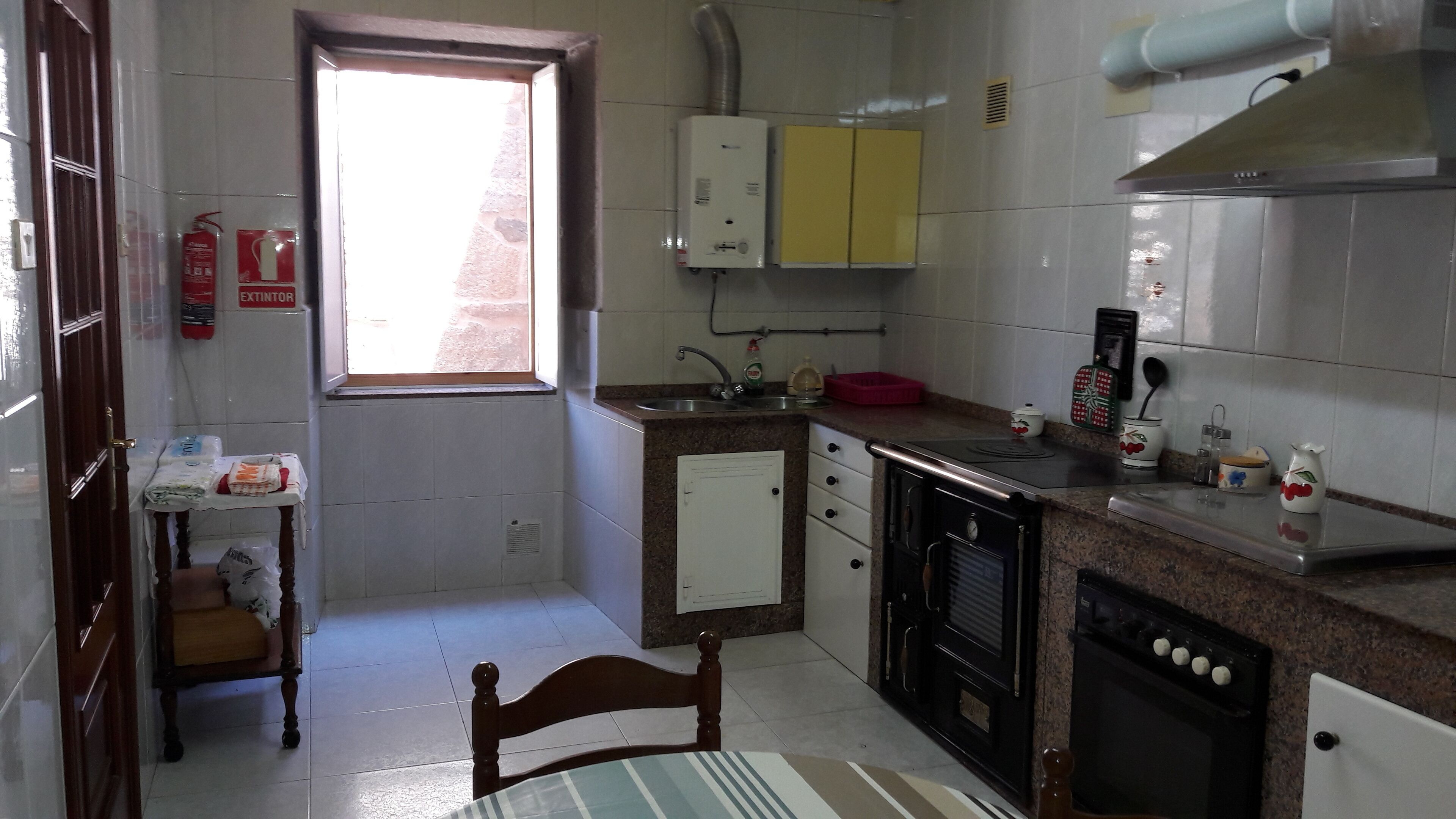 A compact kitchen with a window, a sink, a stove, and a small refrigerator.