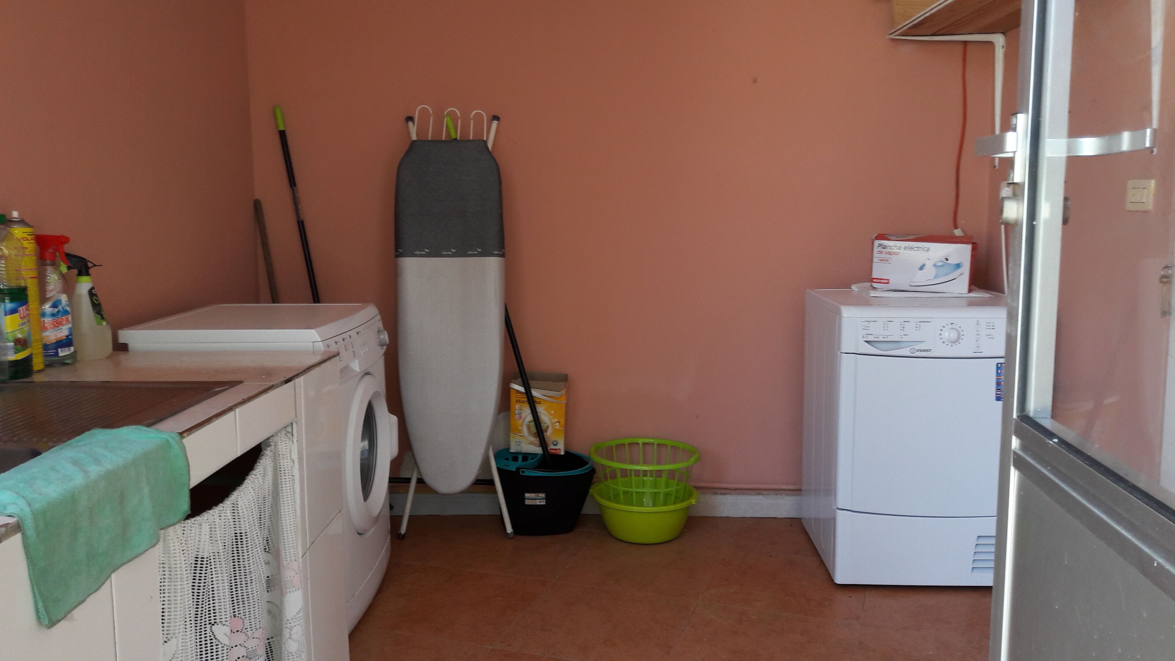 A laundry room with a washing machine, a dryer, a mop, and cleaning supplies.