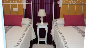 A bedroom with two beds, a nightstand, a lamp, and a curtain.