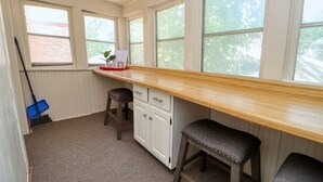 Una cocina con encimera de madera, dos taburetes, un armario y una ventana con vistas a árboles.