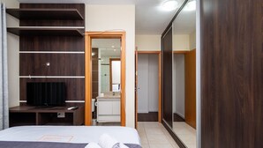 A hotel room with a bed, a TV, a wardrobe, and a bathroom visible through an open door. - MFL1802 (Goiânia)