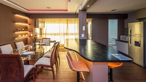 A modern kitchen with a central island, a dining area with a glass table, and a kitchen counter with a microwave and refrigerator. - MFL1802 (Goiânia)