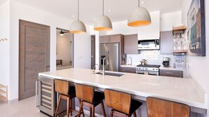 A modern kitchen with a large island, stainless steel appliances, and pendant lighting. - Oceanfront 2BR w/ Two King Beds • Cerritos Beach (Los Cerritos)