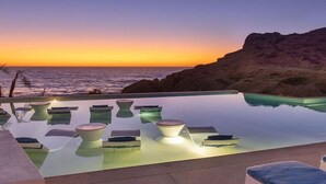 A infinity pool with lounge chairs and a view of the ocean at sunset. - Oceanfront 2BR w/ Two King Beds • Cerritos Beach (Los Cerritos)