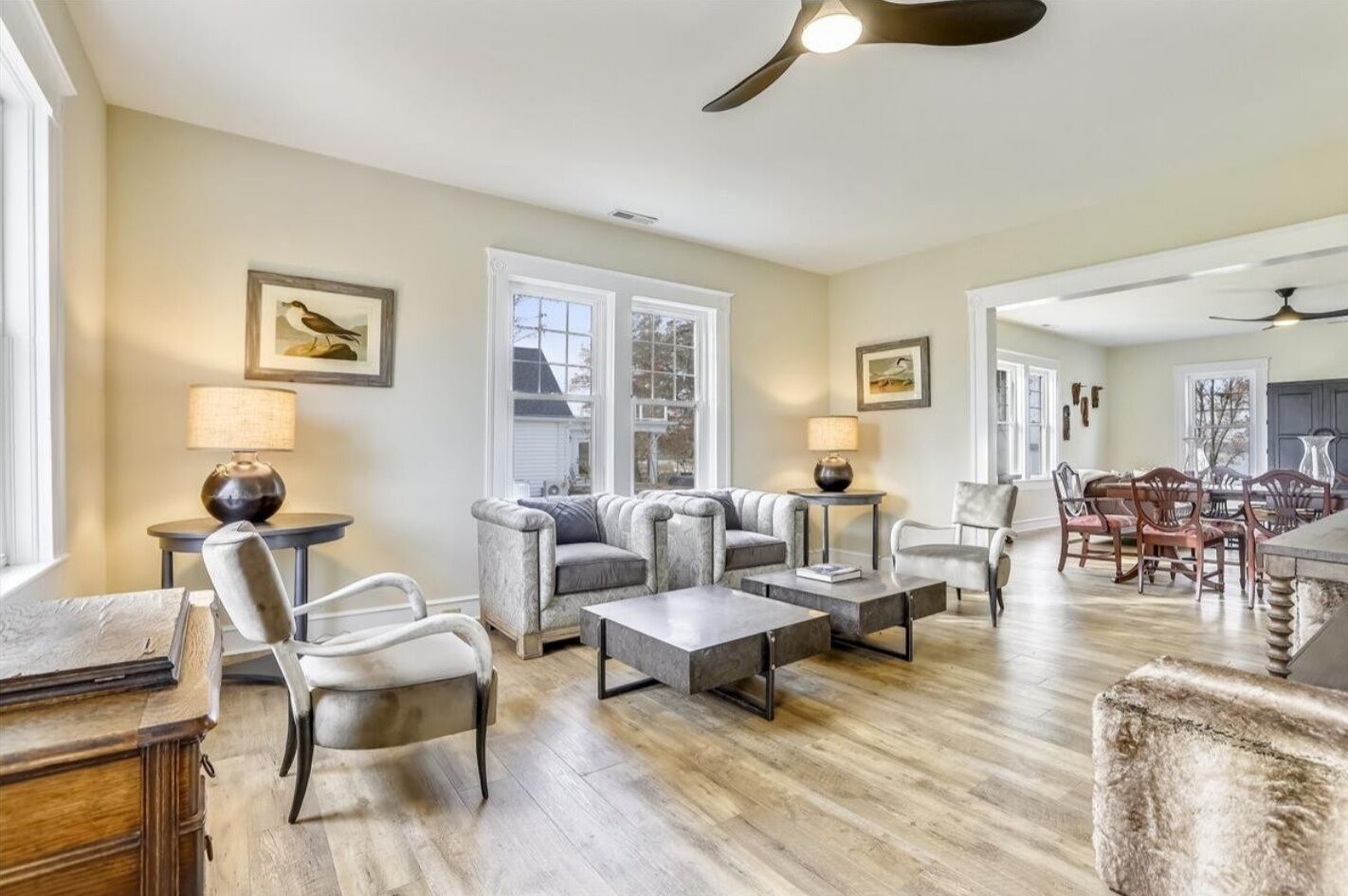 A spacious living room with a fireplace, a dining area with wooden chairs, and a kitchen in the background.