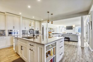 Una cocina amplia con una isla grande, muebles blancos y un diseño moderno.