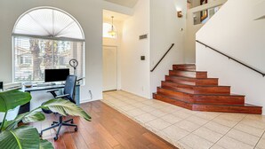 A modern interior with a wooden staircase, a desk with a computer, and large windows. - Outdoor Oasis! Family-Friendly North Phoenix Home (Phoenix)
