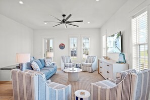 Relax in a spacious living room with a comfortable seating area, TV, and ceiling fan.