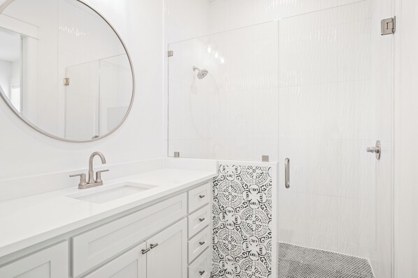 Enjoy a refreshing shower in the sleek bathroom with a large mirror, sink, and glass-enclosed shower.