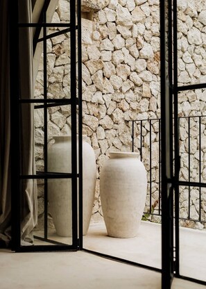 Une piÚce avec un mur en pierre, deux grands vases et un portail en métal.