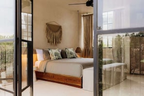 A bedroom with a bed, a hanging macrame wall decoration, and a view of greenery through a glass door. - Casa Majestica Luxury Loft Private Concierge (Tulum)