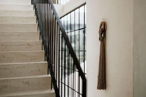 Eine Treppe mit schwarzem Geländer und einer Wanddekoration aus Makramee.