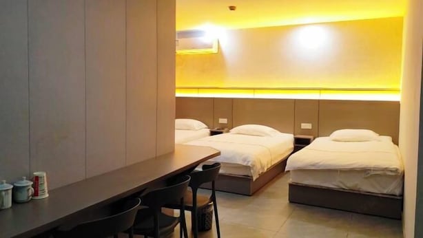Ein Hotelzimmer mit zwei Betten, einem Schreibtisch und Stühlen.