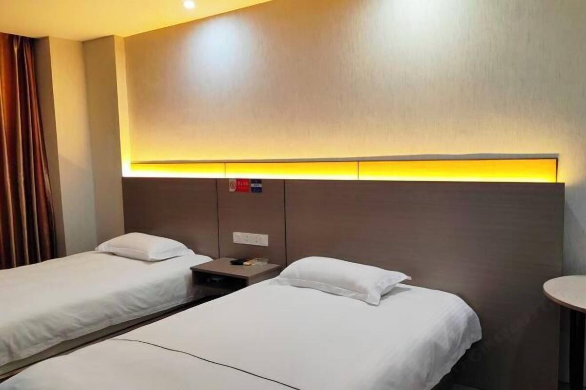 Habitació d'hotel amb dos llits individuals, una tauleta de nit i una taula rodona petita.