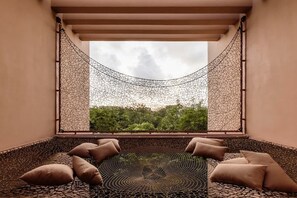 Una hamaca con vistas a la vegetación, un suelo estampado y cojines color beige.
