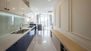 A modern kitchen with white cabinets, a blue countertop, and a large window. - O Clean Home, Vinhomes Central Park (Ho Chi Minh City)