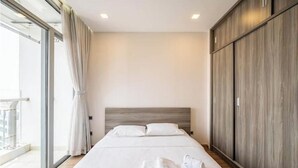 A hotel room with a large bed, a wardrobe, and a sliding glass door to the balcony. - O Clean Home, Vinhomes Central Park (Ho Chi Minh City)