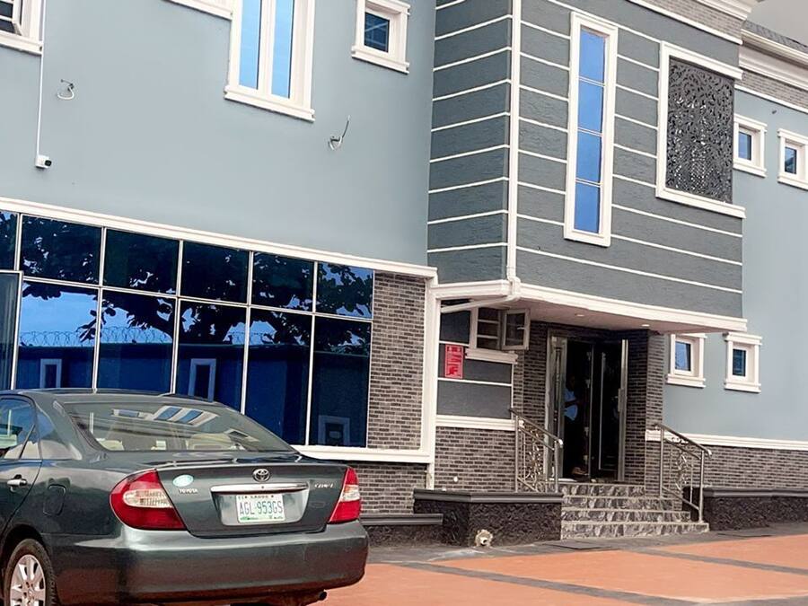 A building with a blue facade, large windows, and a car parked in front.