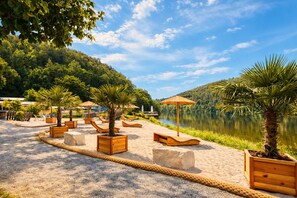 A beachside resort with wooden loungers, palm trees, and a lake view. - Ferienhaus Seeblick am Bitburger See! (Biersdorf am See)