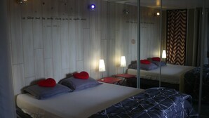 Une chambre d’hôtel avec deux lits, chacun recouvert d’une couvre-lit à motifs différents, un miroir et un mur orné d’une citation.