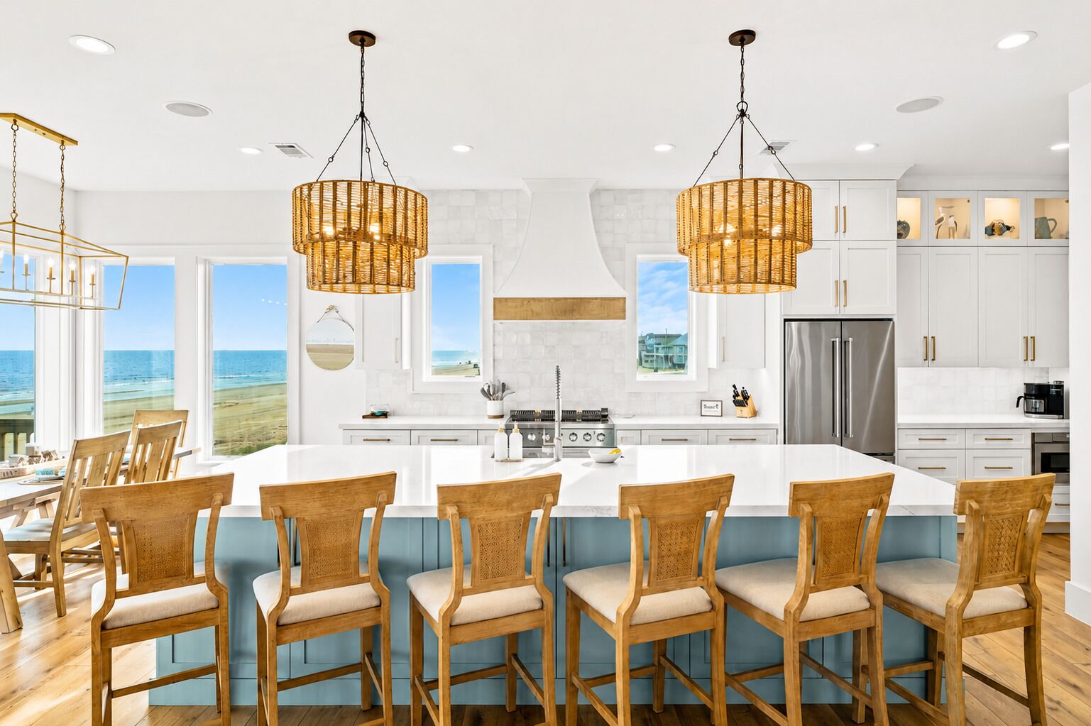 A modern kitchen with a large island, white cabinetry, and a view of the ocean.