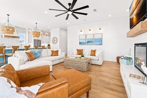 A modern living room with a sectional sofa, a coffee table, and a fireplace. - Beachfront | Heated Pool | Hot Tub | Fenced Yard with Game Area (Crystal Beach)