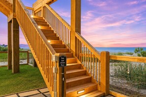 A wooden staircase leading to a beach view with a sign requesting to wash off sand. - Beachfront | Heated Pool | Hot Tub | Fenced Yard with Game Area (Crystal Beach)