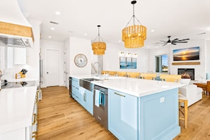 A modern kitchen with a central island, wooden flooring, and pendant lighting.