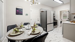 A modern kitchen with a dining area. It includes a refrigerator, oven, and washing machine. - Breath of Fresh Air DT Atlanta (Atlanta)