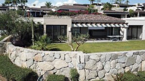 Et moderne hus med stenvæg, terrasse og have.