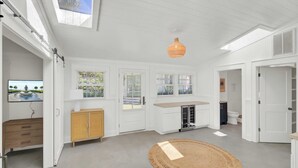 A spacious, well-lit room with a large window, a ceiling fan, and a round woven rug. - 16 29th Avenue Isle of Palms Group Retreat (Isle of Palms)