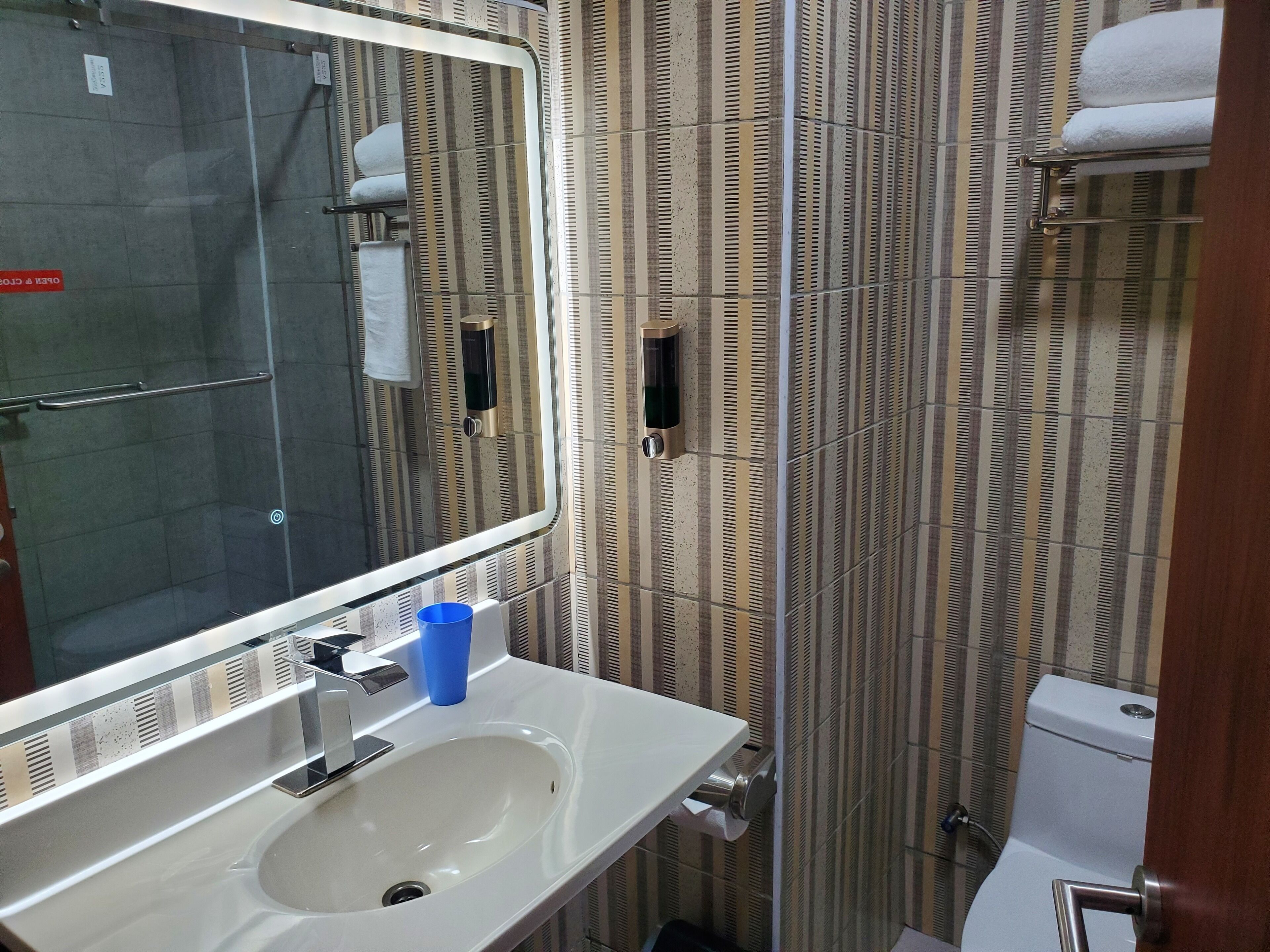 A bathroom with a white sink, a mirror, a towel rack, and a striped wall.