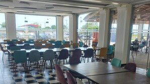A spacious indoor area with checkered flooring, multiple tables, and chairs arranged for dining.