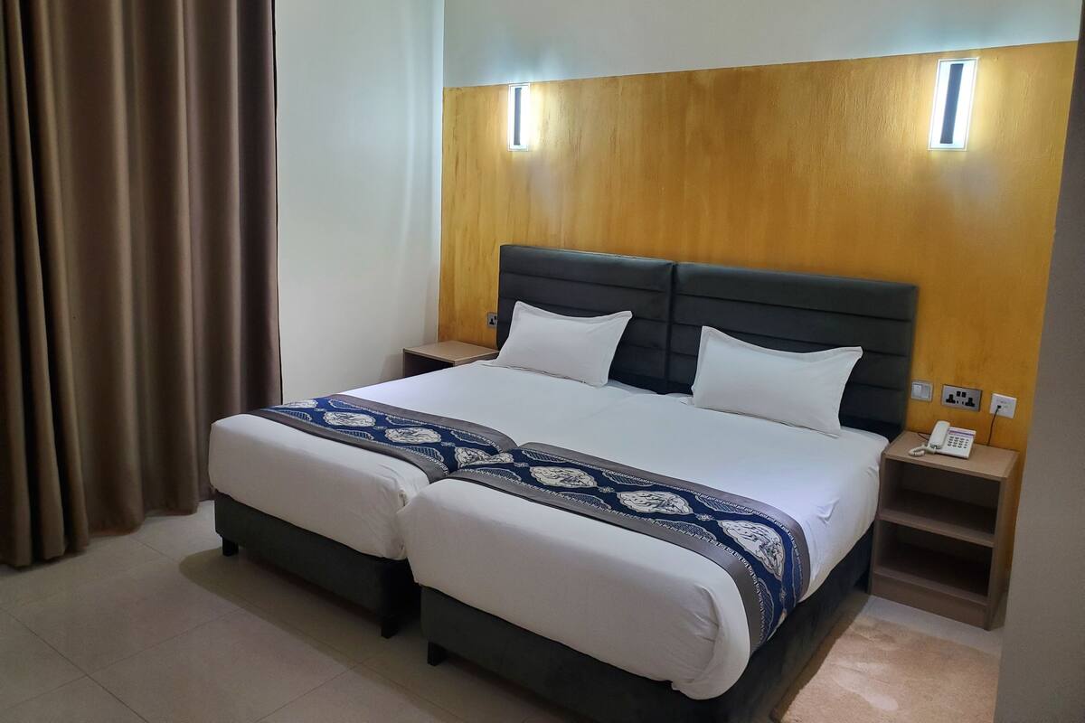 A double bed with a wooden headboard, two bedside tables, and a nightstand with a phone.