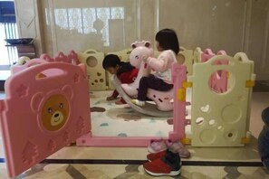 Un'area giochi per bambini con struttura rosa e bianca, che include un cancello a forma d'orso e una zona giochi circolare.
