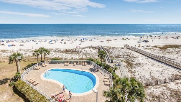 Un resort sulla spiaggia con piscina, sdraio e vista sull'oceano.