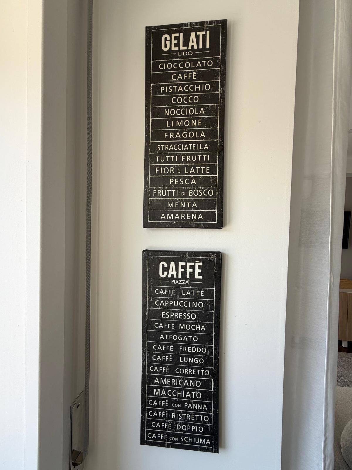 Two black signs with white text listing various gelati and caffe options.