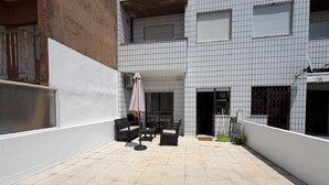 A courtyard with outdoor seating, a covered area, and a building with a tiled facade. - Nove de Julho Apartment (Porto)