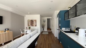 A modern kitchen with a built-in oven, a dining area with a bench, and a hallway leading to a staircase. - Nove de Julho Apartment (Porto)
