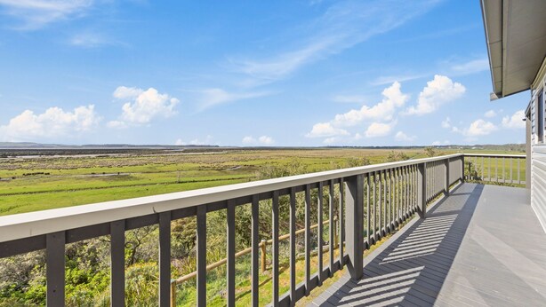 Een balkon met uitzicht op een grasrijk landschap en verre heuvels.